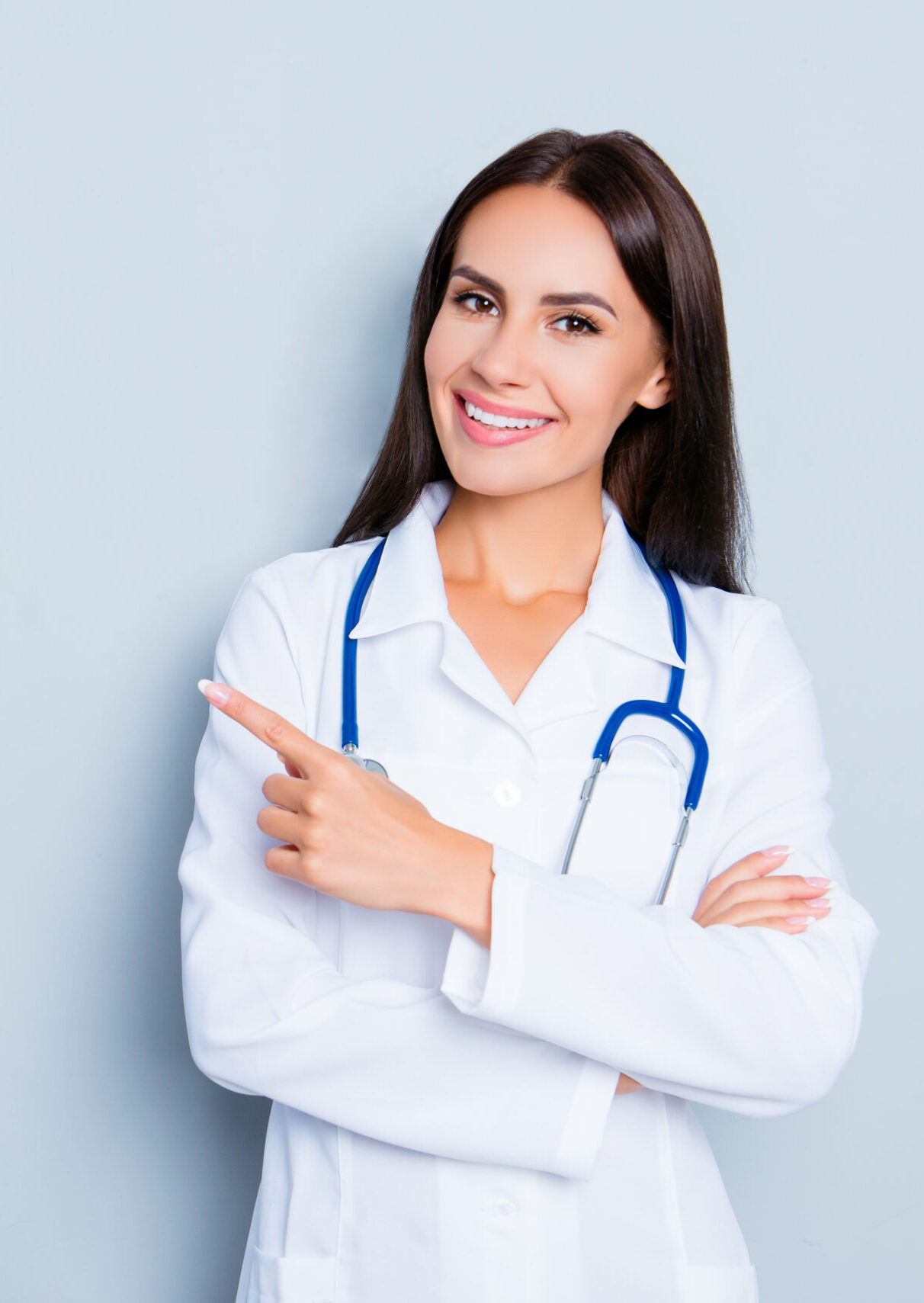 Smiling happy doctor pointing with finger on blue background